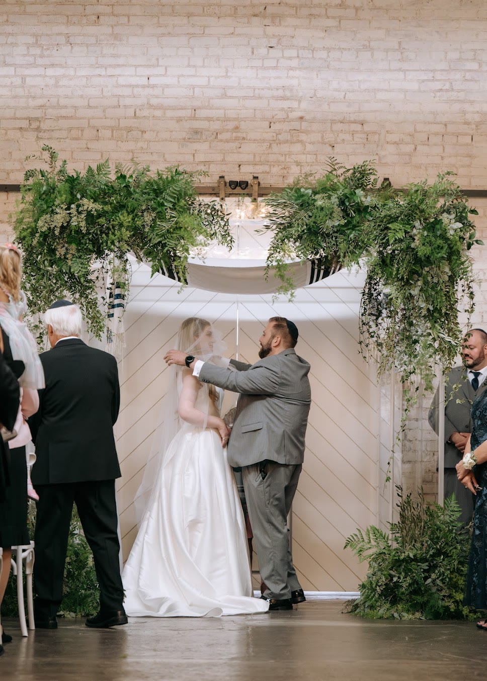 A couple under the chuppah dressed with greenery