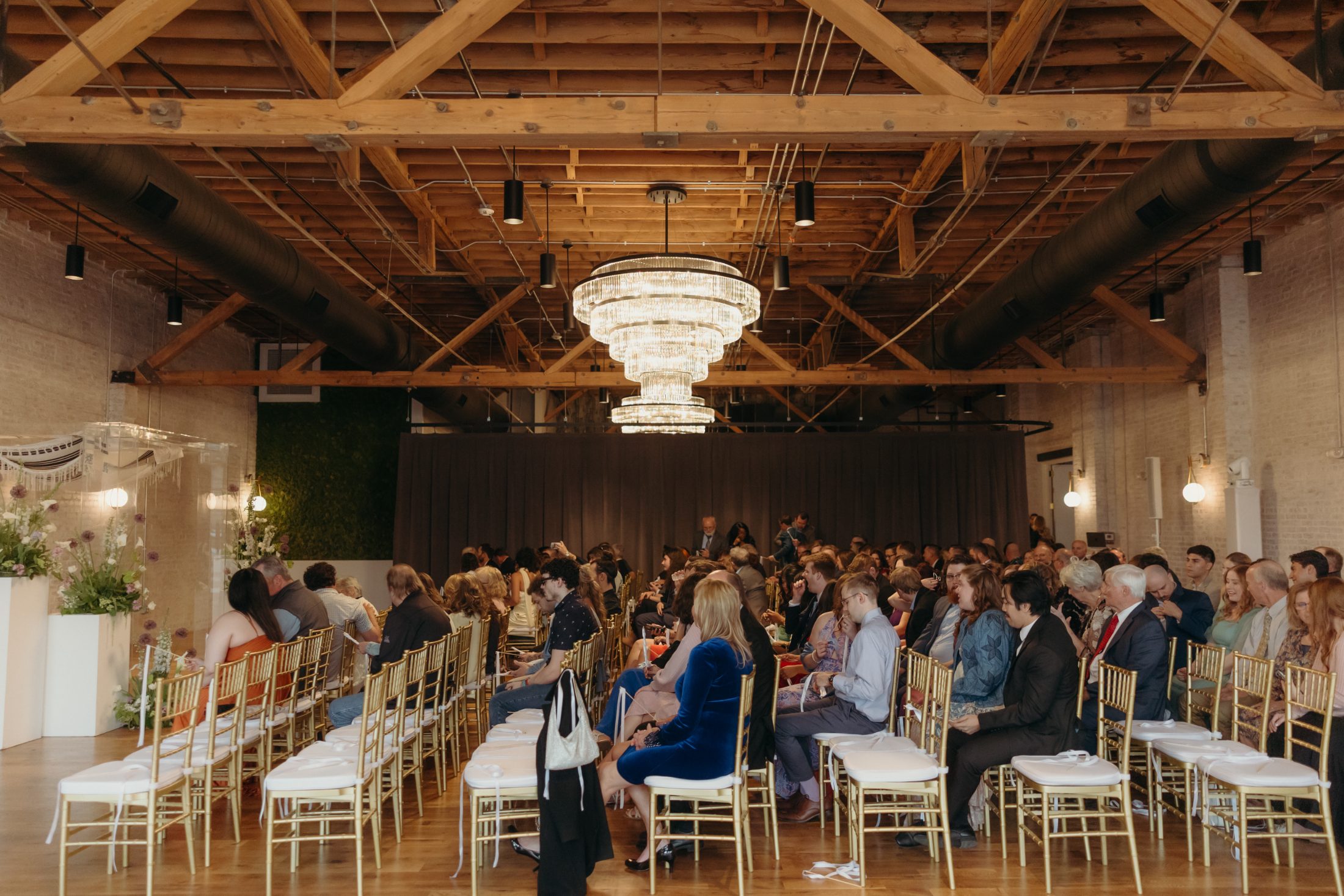 Guests seated for a ceremony beneath the chandelier