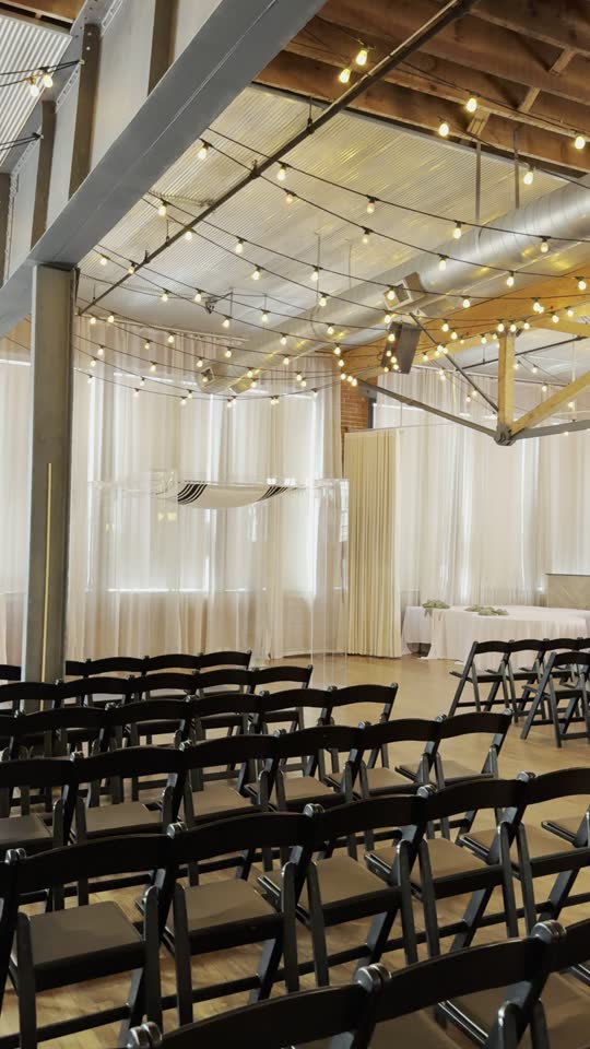 A ceremony set with the clear acrylic chuppah, string lights, and rows of chairs