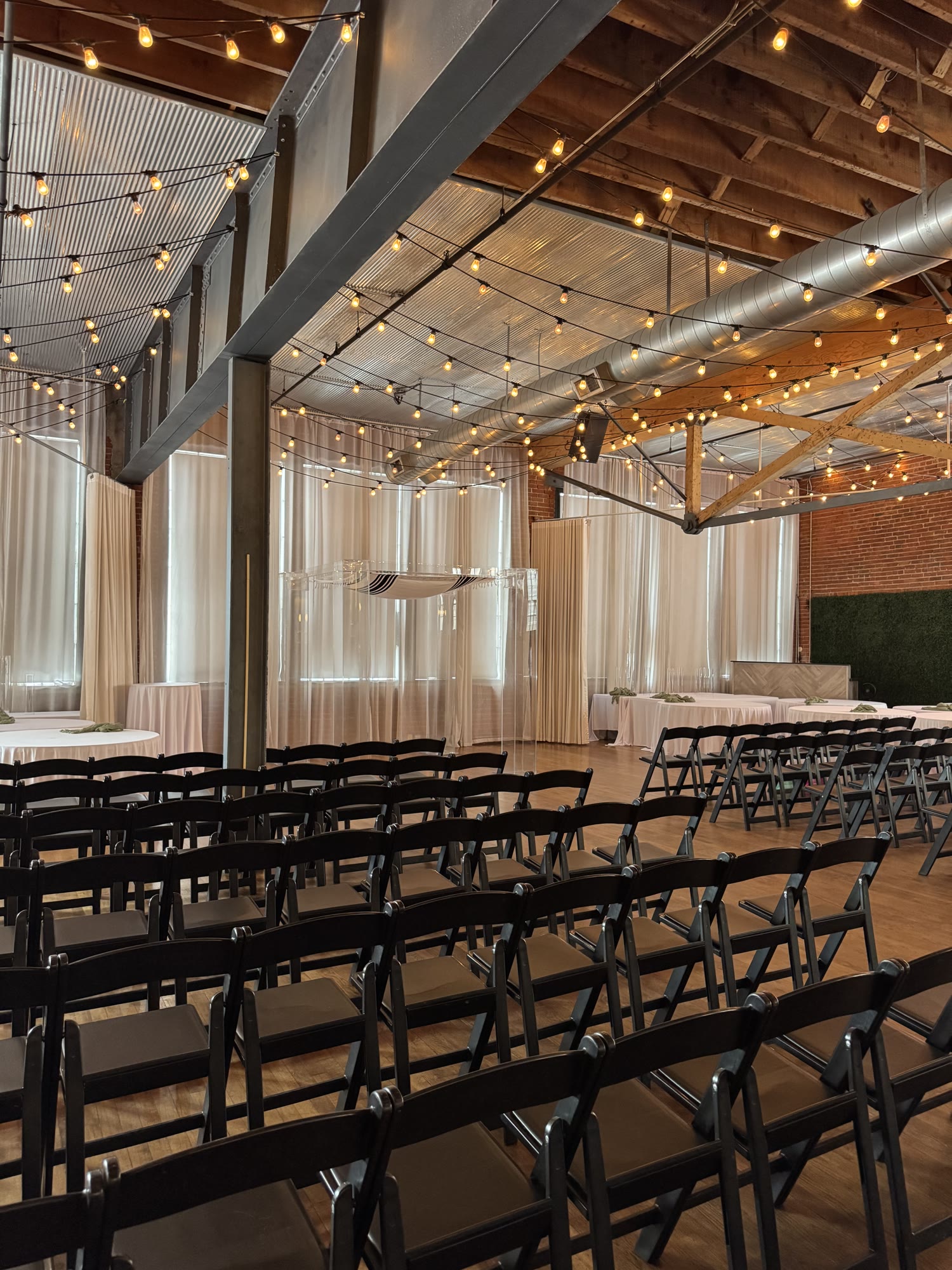 The ceremony room set with rows of chairs under bistro lights